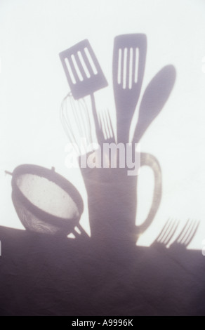 Ombra nella luce calda sul panno pallido o tenda di utensili da cucina in caraffa con setaccio e tabella le forche si trovano a fianco Foto Stock