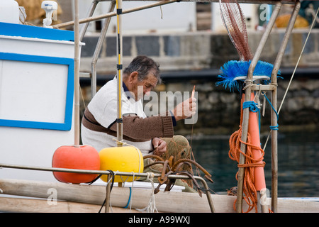 Pescatore siciliano riparare reti Foto Stock
