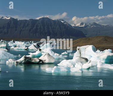 Iceberg galleggianti in laguna glaciale con scuri monti dietro a Jokulsarlon nel sud est dell'Islanda Foto Stock
