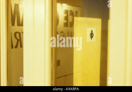 Vista della porta interna con segno per womens wc in serata calda luce con finestra enigmatico riflessioni di gelato segno Foto Stock