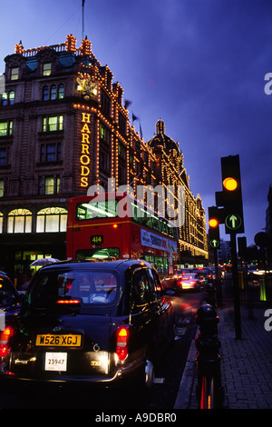 Rush Hour traffico fuori i famosi magazzini Harrods accesa fino al tramonto nella città di Londra Inghilterra REGNO UNITO Foto Stock