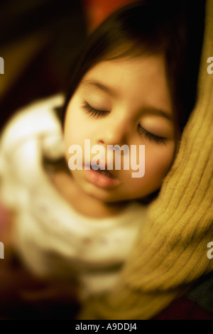 Testa e spalle ritratto di due anno vecchia ragazza dorme tra le braccia della mamma Foto Stock