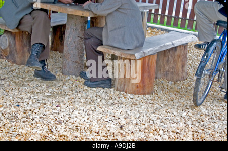 Due colleghi seduti ad un tavolo esterno al negozio di alimentari e un ragazzo con la bicicletta. Sadykierz Polonia Foto Stock