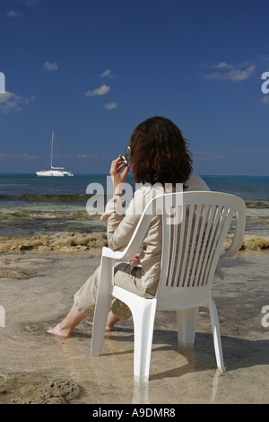Donna che utilizza il telefono cellulare sulla spiaggia Foto Stock