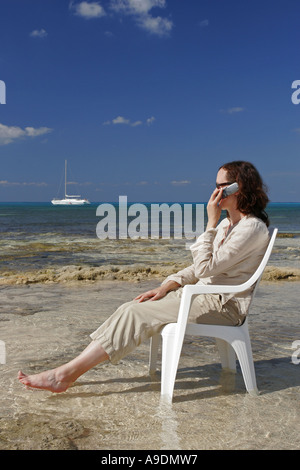 Donna che utilizza il telefono cellulare sulla spiaggia Foto Stock