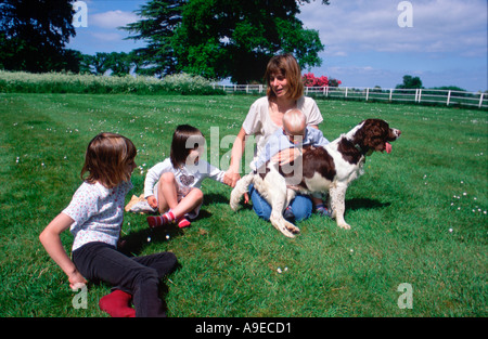 Gruppo di famiglia in estate sul prato con cocker spaniel cane madre 33 anni figlia di 4 anni la figlia di 6 anni figlio 1 anno Foto Stock