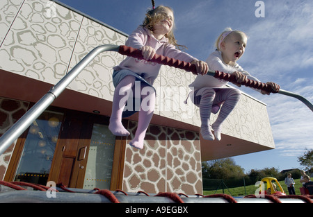 Due quattro 4 anno di età le ragazze di rimbalzo con glee su un trampolino Foto Stock