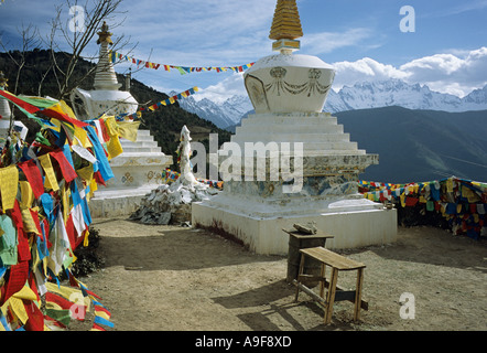 Gruppo di stupa e bandiere di preghiera del santo sito tibetano in Feilai Si vicino alla città di Deqin nella provincia dello Yunnan in Cina con le montagne in Foto Stock