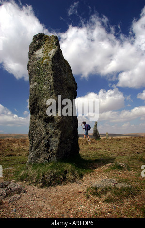 Un viandante passa le pietre permanente a Stalldown Barrow su Dartmoor sotto il cielo blu e nuvole Foto Stock