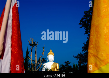 Grande oro bianco e la statua del Buddha con cielo blu dietro e due bandiere in primo piano Foto Stock