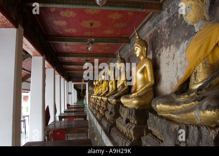 Golden Statue di Buddha in una linea a un tempio thailandese Foto Stock