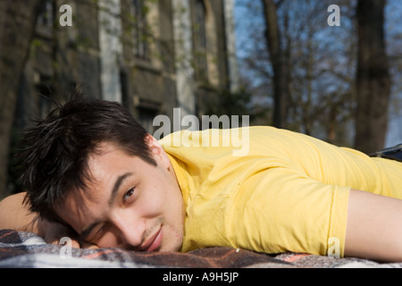 L'Uomo sdraiato su una coperta picnic nel parco Foto Stock