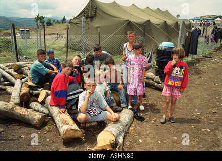 I bambini in un accampamento militare in attesa di cibo e sostegno europeo americano attento ragazzo caucasico persona chat chat c Foto Stock