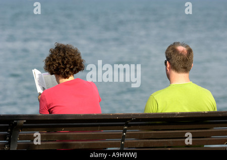 Giovane seduto sul banco a lago Foto Stock