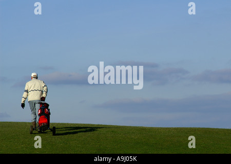 Il golfer tirando carrello da golf Foto Stock