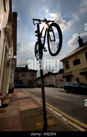 Un Raleigh Mountain bike è fissato sulla parte superiore di un parcheggio polo di restrizione su una strada della città. Foto Stock