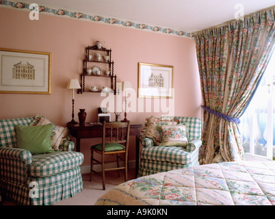 Verde e bianco verificare poltrone in camera rosa con rosa e floreale verde tende a motivi geometrici e trapunta corrispondenti sul letto Foto Stock