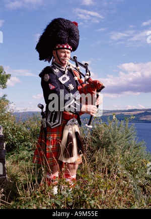 dh Scottish Highlander BAGPIPES SCOTLAND Kilt Highland Clan vestito Highlands bagpiper lone piper suonando un tradizionale uomo di musica tartan Foto Stock