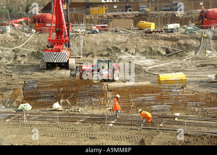 Sito in costruzione operai assemblaggio in acciaio gabbie di rinforzo pronto per far cadere in un mucchio di fori per la cementificazione Foto Stock