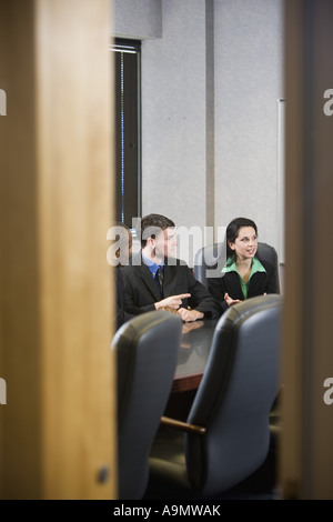 I dirigenti aziendali riunione in una sala conferenze osservata attraverso una porta Foto Stock