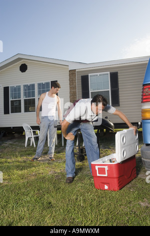 Uomo che guarda nel torace di ghiaccio mentre un altro uomo orologi, nella parte anteriore del rimorchio home Foto Stock