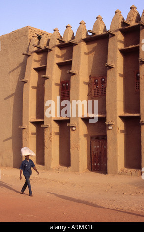 Un uomo cammina passato di mattoni di fango in architettura i Dogon città di Bandiagara, Mali, Africa occidentale Foto Stock