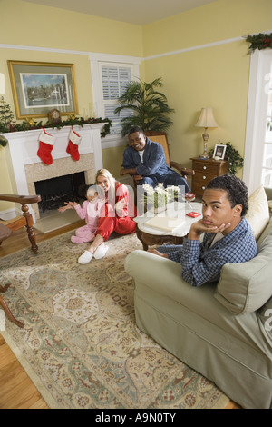 Famiglia in pigiama seduti davanti al camino decorato per il Natale Foto Stock