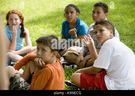 I bambini seduti in cerchio sull'erba a un parco Foto Stock