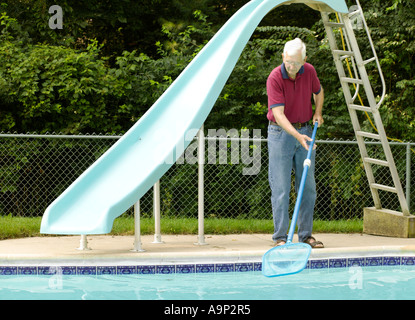 Uomo anziano pulizia piscina con net Foto Stock