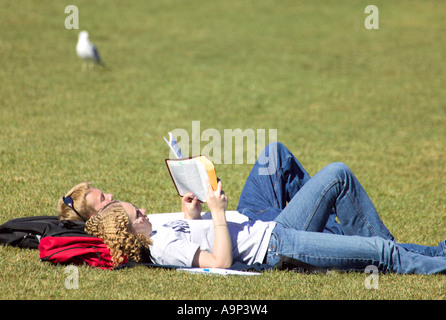 Coppia giovane giacente sulla lettura di erba Foto Stock