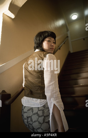 Vista di una giovane donna asiatica al fondo della scala Foto Stock