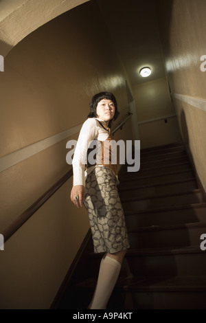 Vista di una giovane donna asiatica al fondo della scala Foto Stock