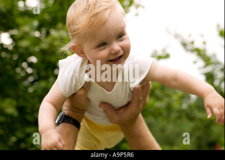 Happy Baby girl detenute aloft Foto Stock