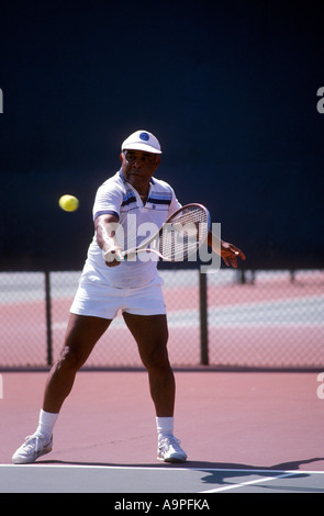 Senior nero colpendo il rovescio girato durante il gioco di tennis. Foto Stock