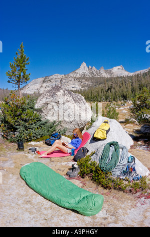 Donna relax nel camp sotto i picchi di eco ingranaggio di arrampicata visibile il Parco Nazionale di Yosemite in California Foto Stock