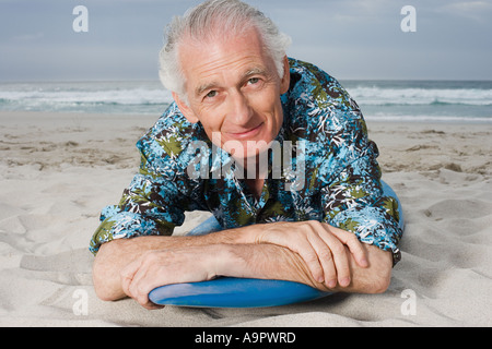 Senior uomo disteso sulla tavola da surf Foto Stock