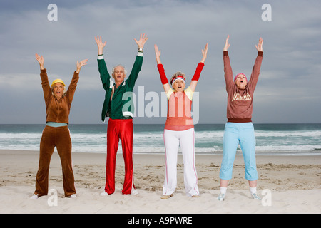 Quattro adulti senior stretching sulla spiaggia Foto Stock