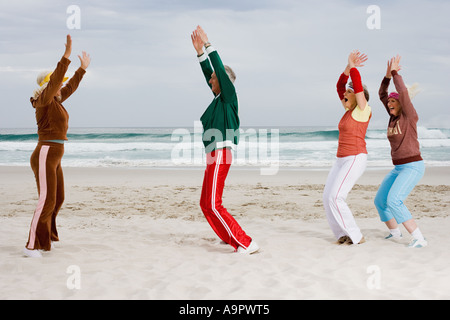 Quattro senior adulti che esercitano sulla spiaggia Foto Stock