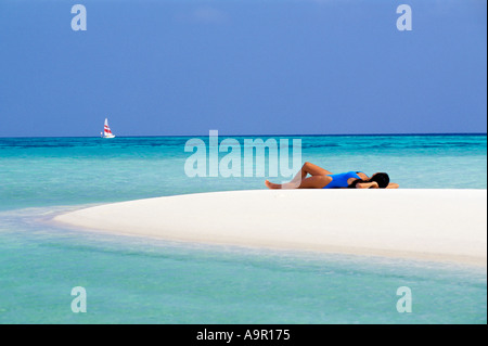 Donna sdraiata sulla sandbar con passaggio di catamarano durante l isola delle vacanze in paradiso Foto Stock