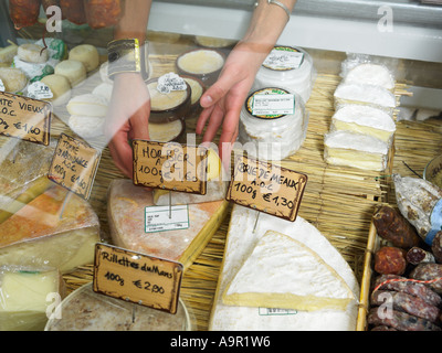 Donna di raggiungere nel display di delicatessen Foto Stock