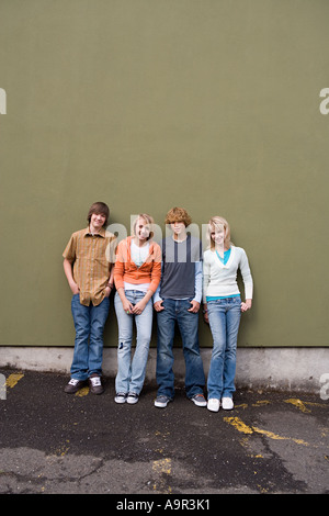 Quattro adolescenti appoggiato contro una parete Foto Stock