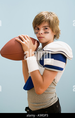 Ragazzo nel football americano uniforme sfera di trattenimento Foto Stock