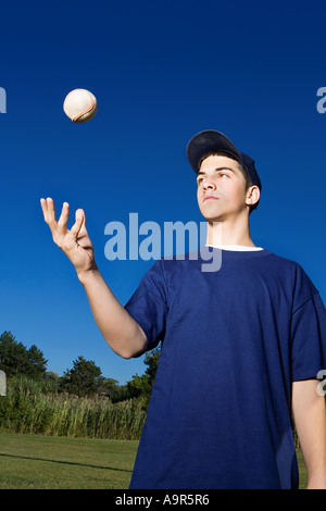 Ragazzo adolescente di baseball di lancio in aria Foto Stock