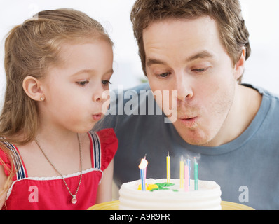 Padre e figlia che spegne le candeline sulla torta del compleanno Foto Stock