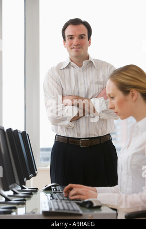 Imprenditore con le braccia incrociate dietro imprenditrice Foto Stock