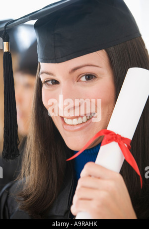 Donna che indossa il cappuccio di graduazione e camice con diploma Foto Stock
