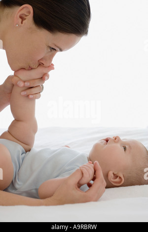 Madre kissing baby s piedi Foto Stock