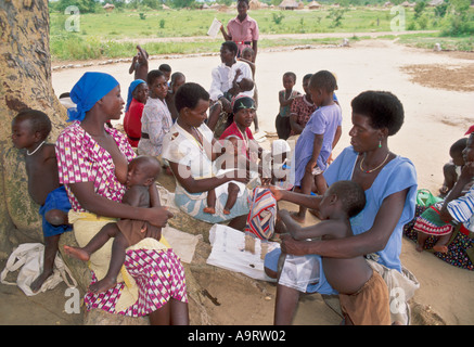 Donne e bambini con operatori sanitari in una clinica bush all'aperto. Nr Binga, Zimbabwe Foto Stock
