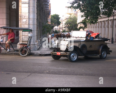 Cuba havana giovane donna alla guida di classic openair sportscar e uomo su cycletaxi Foto Stock