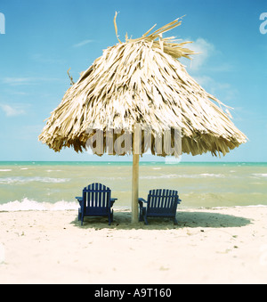 Due sedie a sdraio sotto la palapa su una spiaggia a sud del Belize Foto Stock
